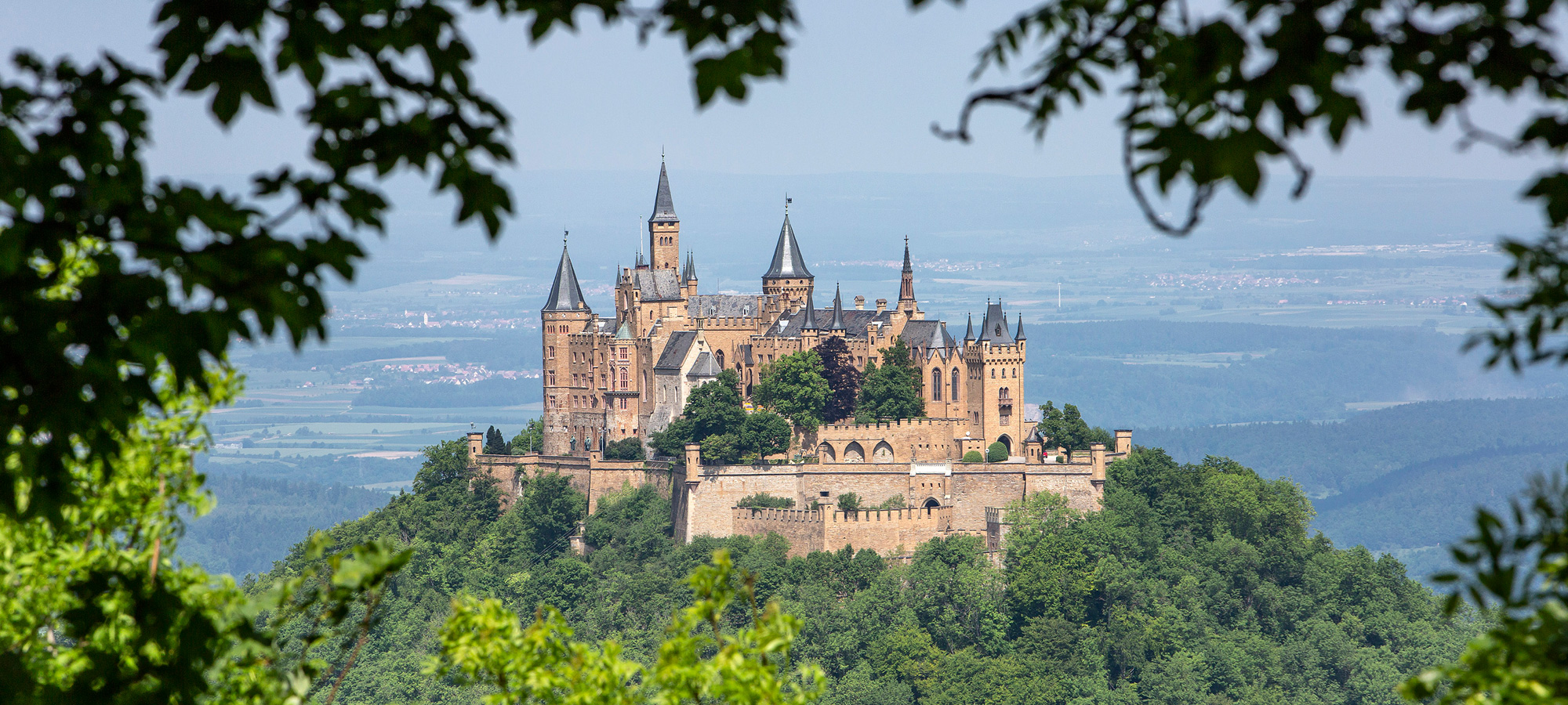Burg Hohenzollern liegt am Rande der Schwäbischen Alb. Im Hintergrund ist Bisingen bei Balingen zu sehen.